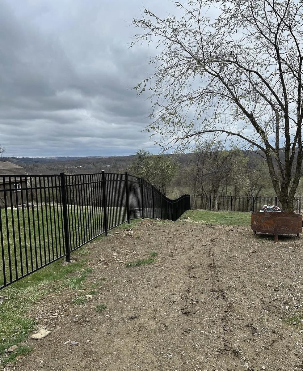 Black aluminum fence following the slope of a hillside backyard