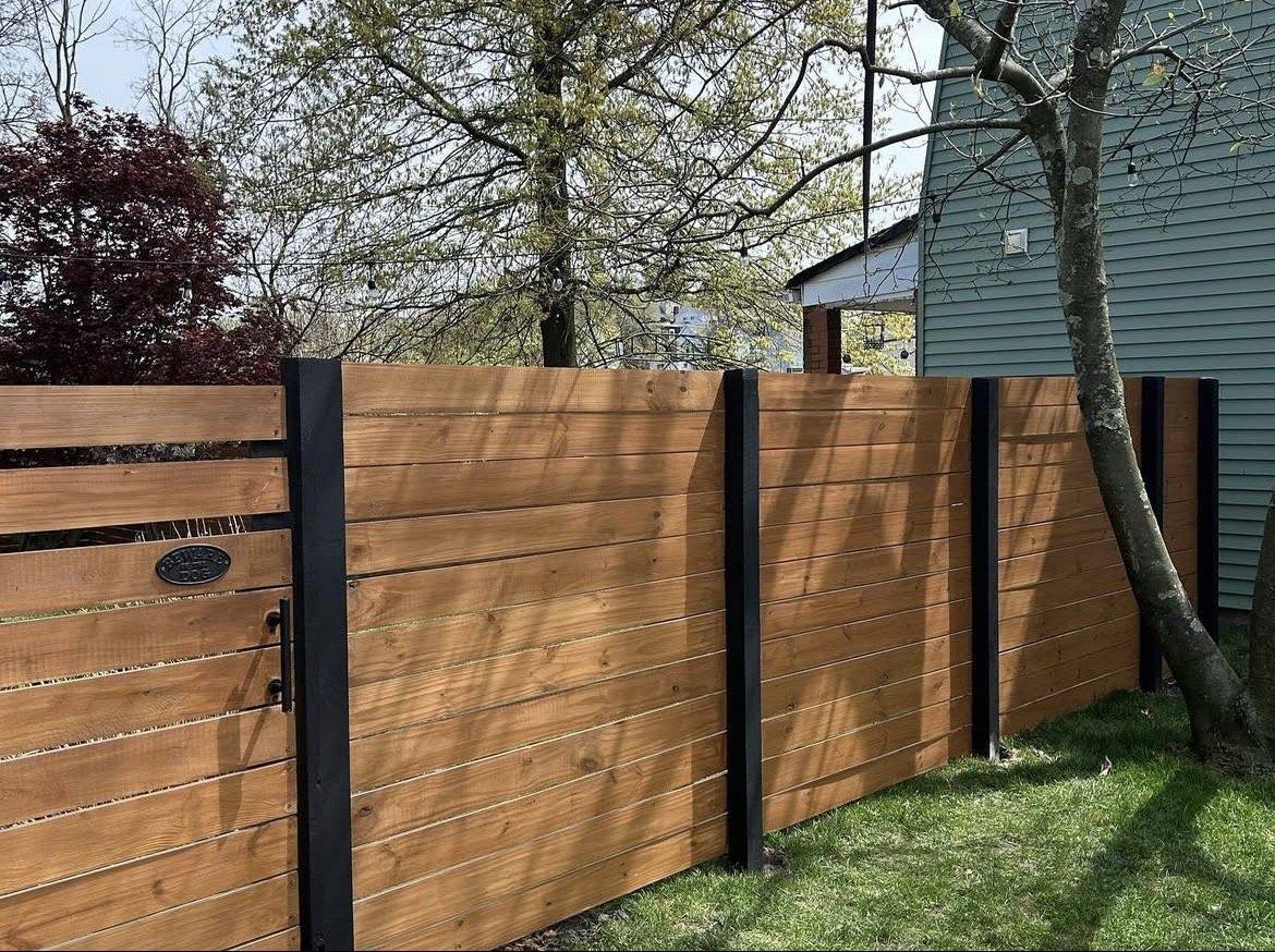 Horizontal stained cedar fence with black posts and a matching gate, built by Usenicnik Contracting