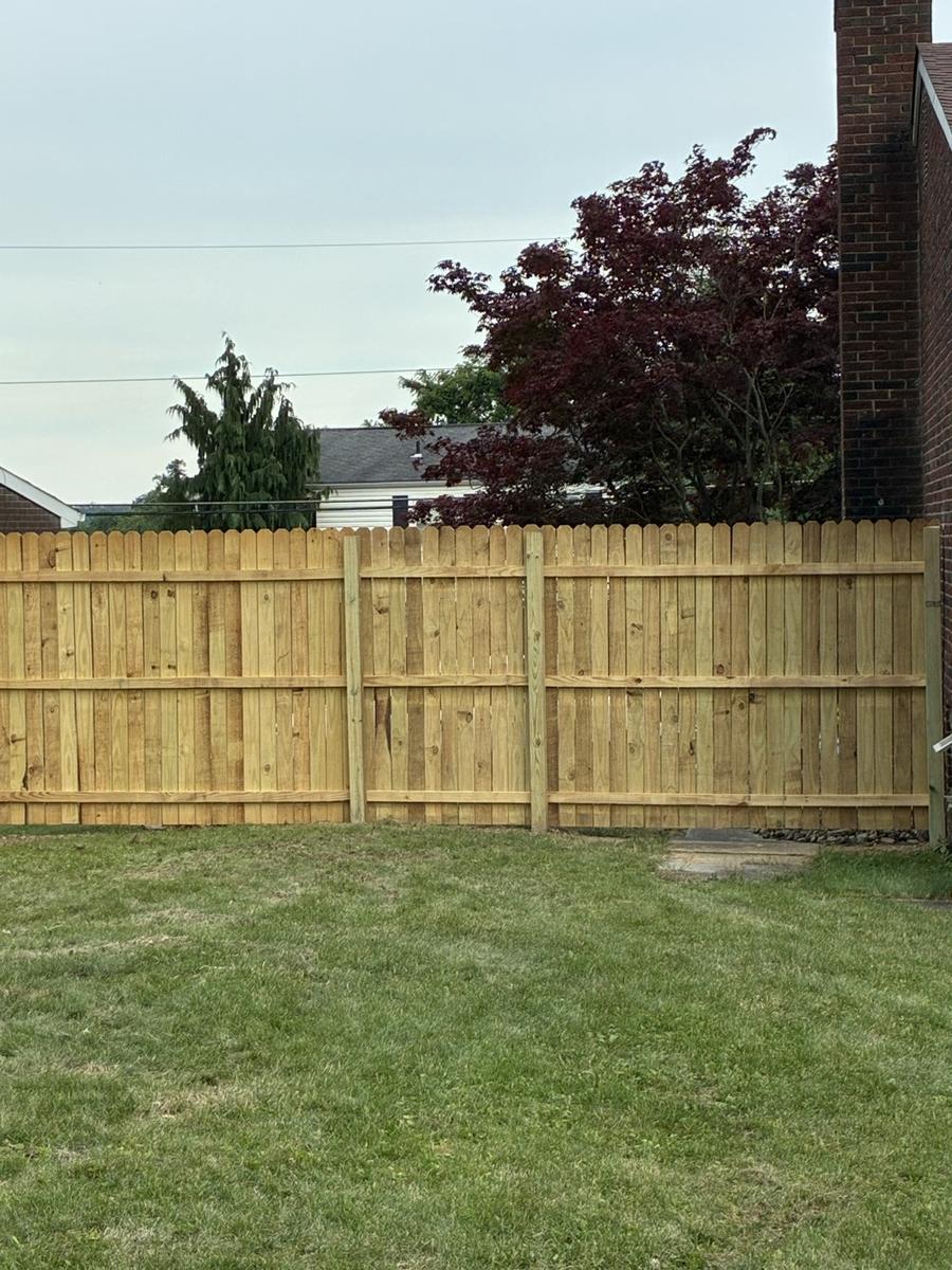 Long run of new wood privacy fence across a backyard lawn